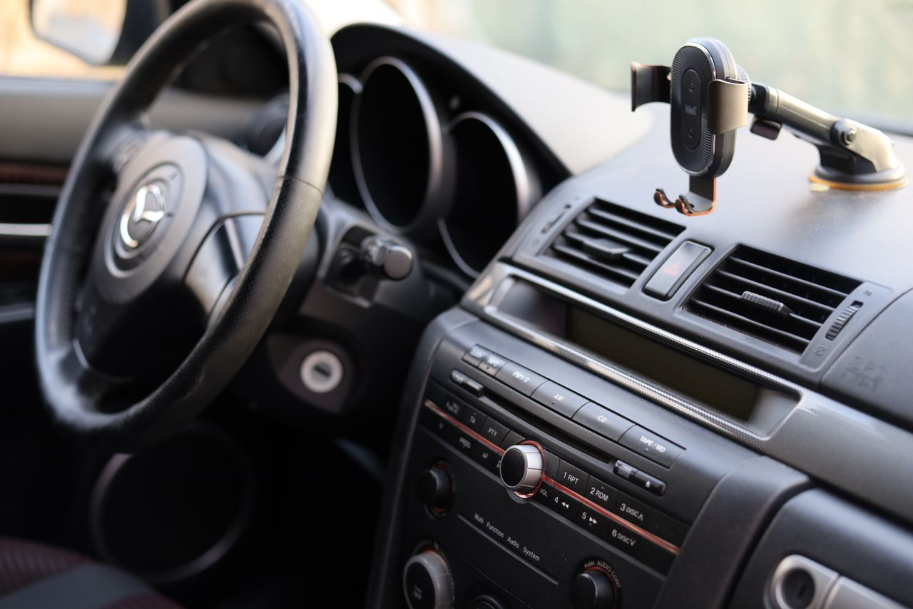 footer-01 Close-up of a car dashboard featuring a steering wheel and phone holder, ideal for automotive insights.
