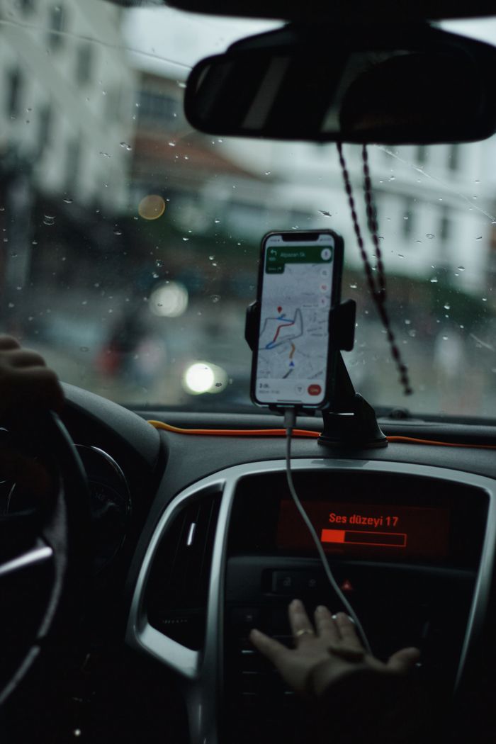 about-02 View of a car interior focusing on GPS navigation with raindrops on windshield.