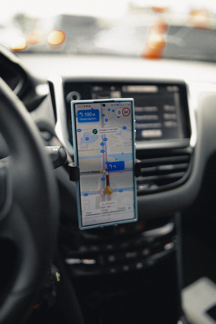 footer-02 A close-up of a smartphone displaying GPS navigation in a modern car interior.