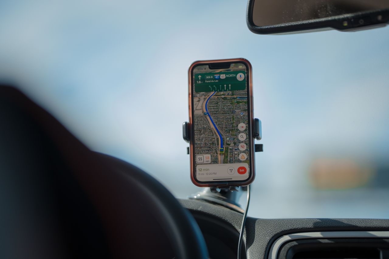 awards-img A smartphone with GPS navigation app mounted on a car dashboard during a road trip.